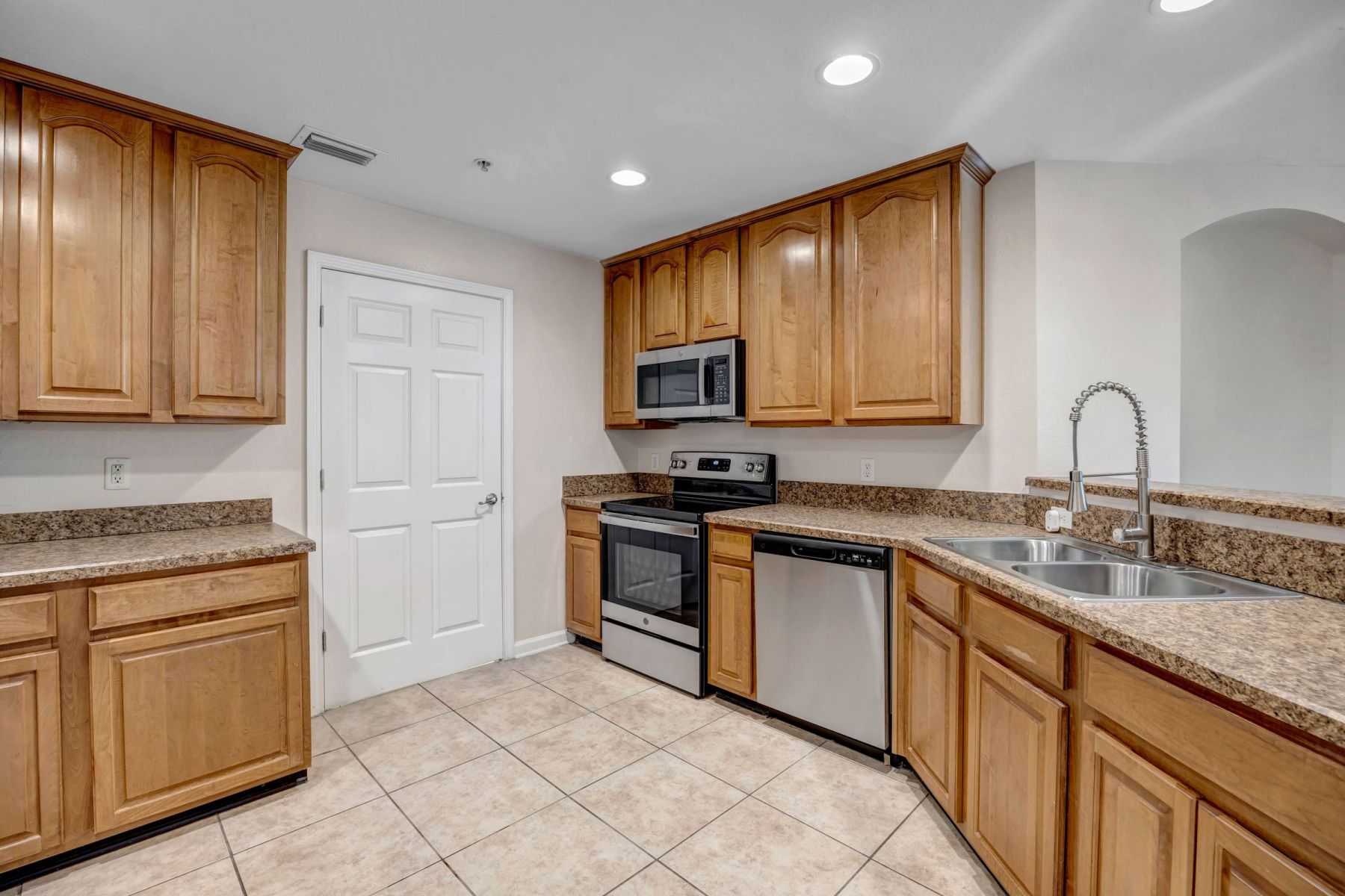 Empty room with wood floors, ceiling fan, and sliding glass door leading to a patio with vertical blinds at Apex West Midown.